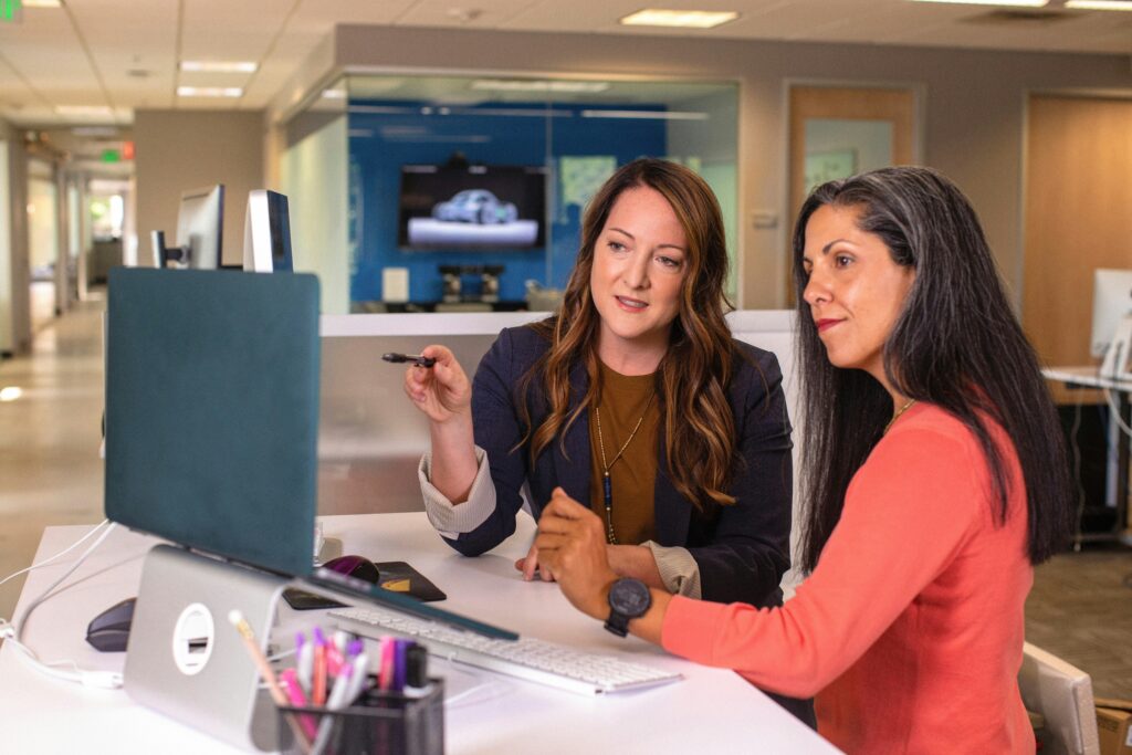 Two women in a corporate office reviewing consumer research findings on purchase behavior and customer journey insights.
