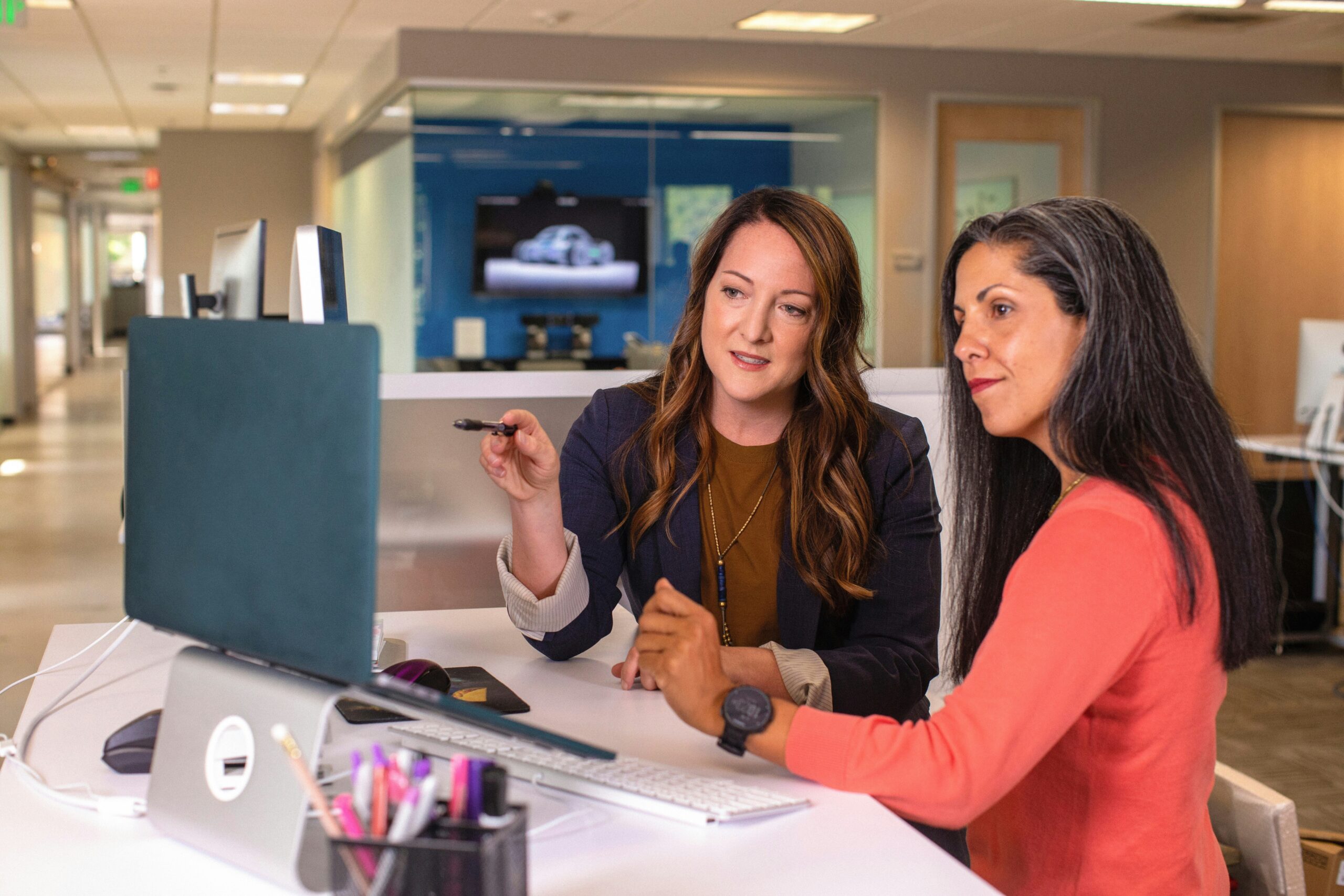 Two women in a corporate office reviewing consumer research findings on purchase behavior and customer journey insights.