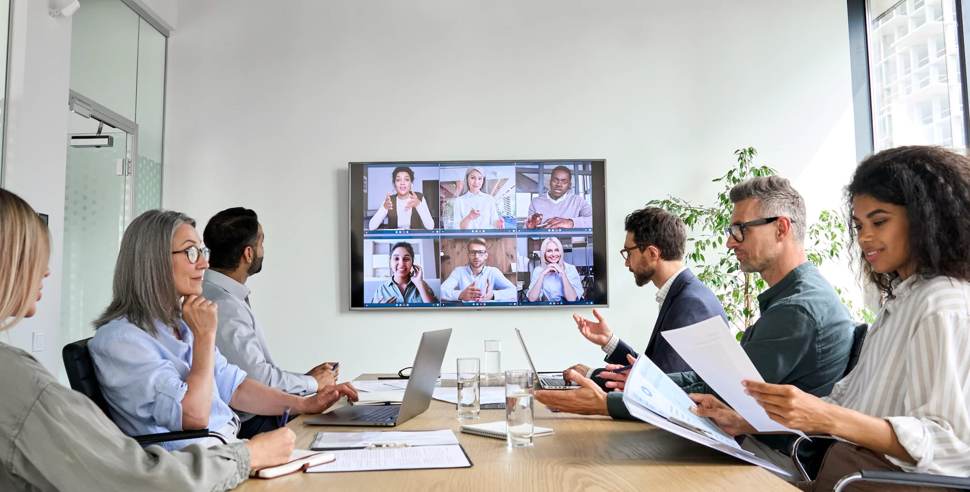 Collateral Testing Market Research with group of professionals at boardroom table and on zoom with remote colleagues discussing performance of business. Olinger Market Research Company