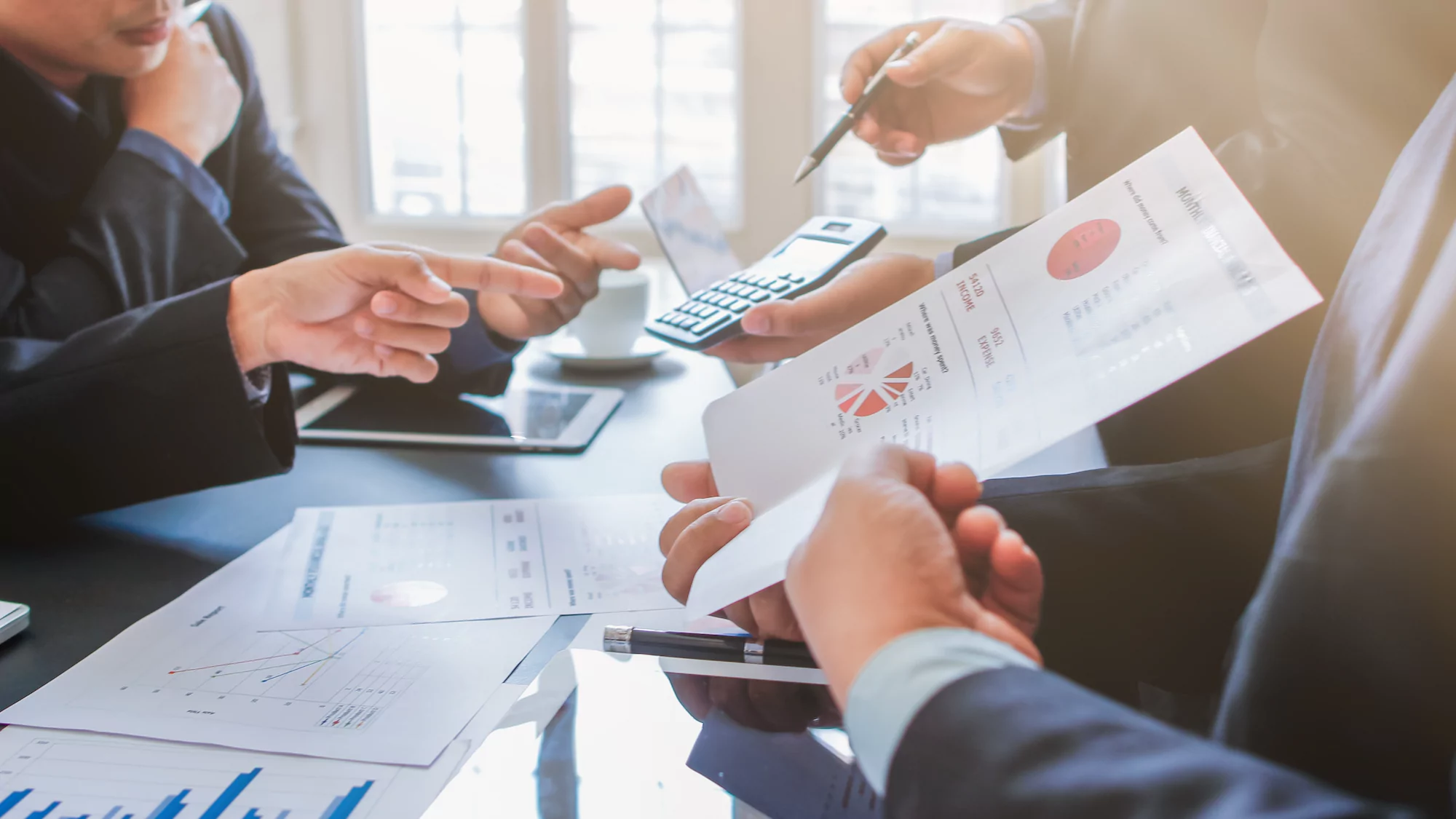 Professionals pointing to and passing around papers with charts and graphs that represent collateral testing market research